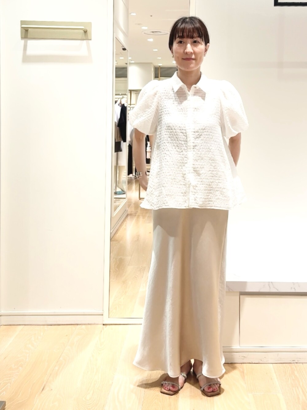 ベージュ系のスカート、ホワイト系のシャツ/ブラウス、ゴールド系のバレッタ/ヘアクリップを着用したレディースの夏コーディネートの7枚目の写真