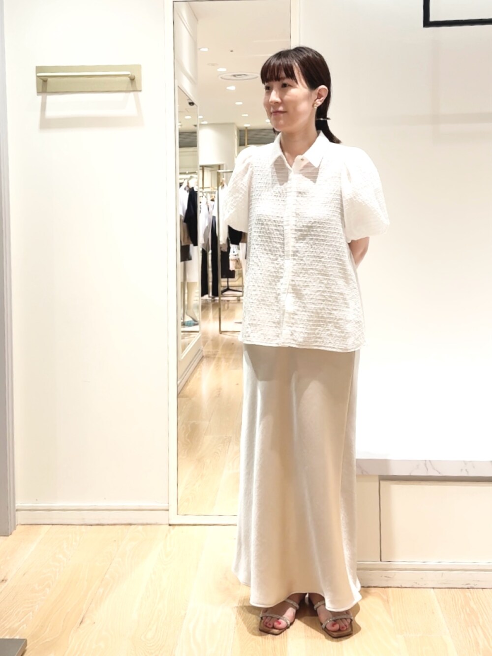 ベージュ系のスカート、ホワイト系のシャツ/ブラウス、ゴールド系のバレッタ/ヘアクリップを着用したレディースの夏コーディネートの8枚目の写真