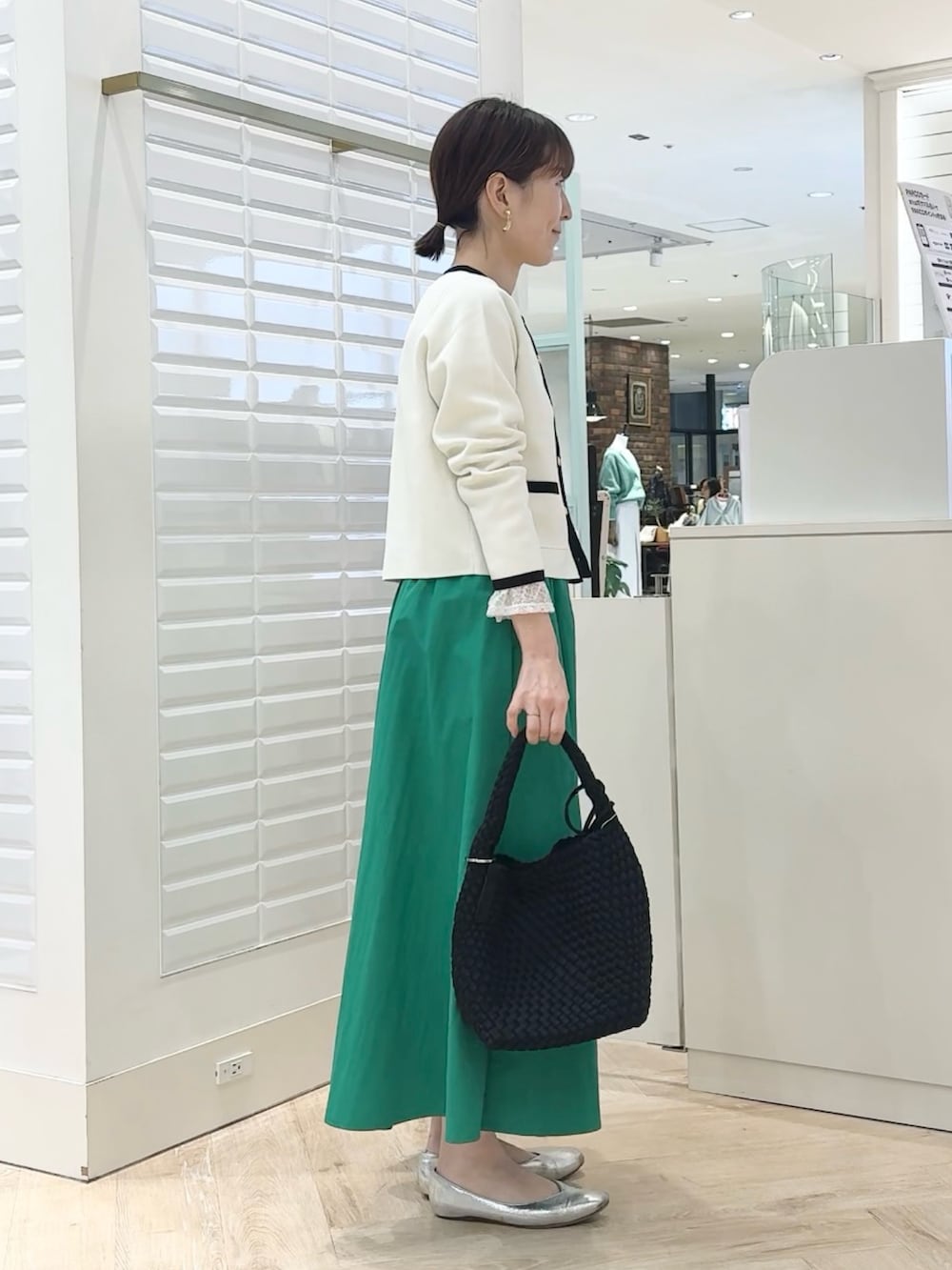 ホワイト系のカーディガン/ボレロ、グリーン系のスカート、ブラック系のショルダーバッグを着用したレディースの春コーディネートの3枚目の写真