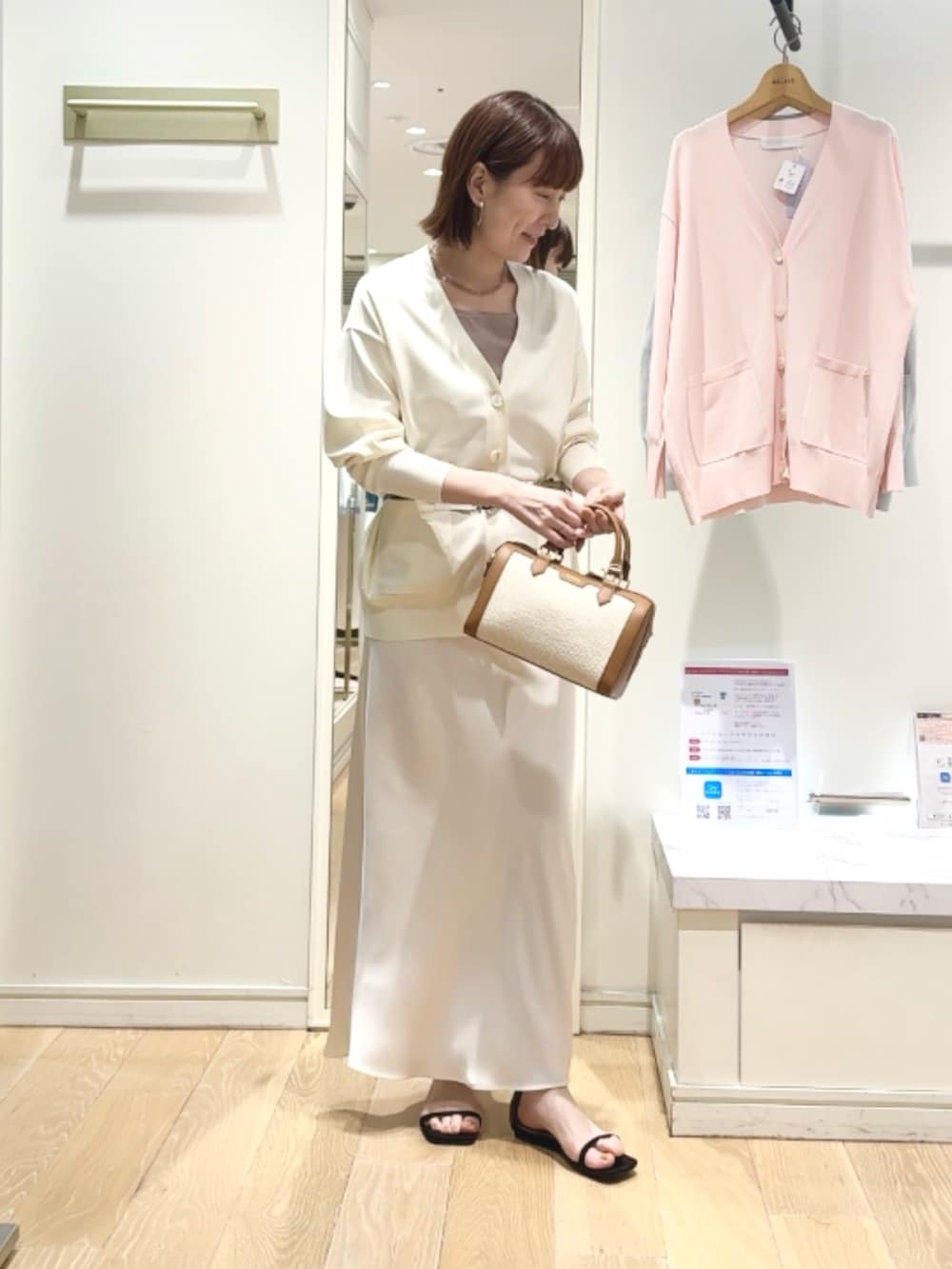 ベージュ系のタンクトップ、ホワイト系のスカート、ブラウン系のボストンバッグを着用したレディースの春コーディネートの2枚目の写真