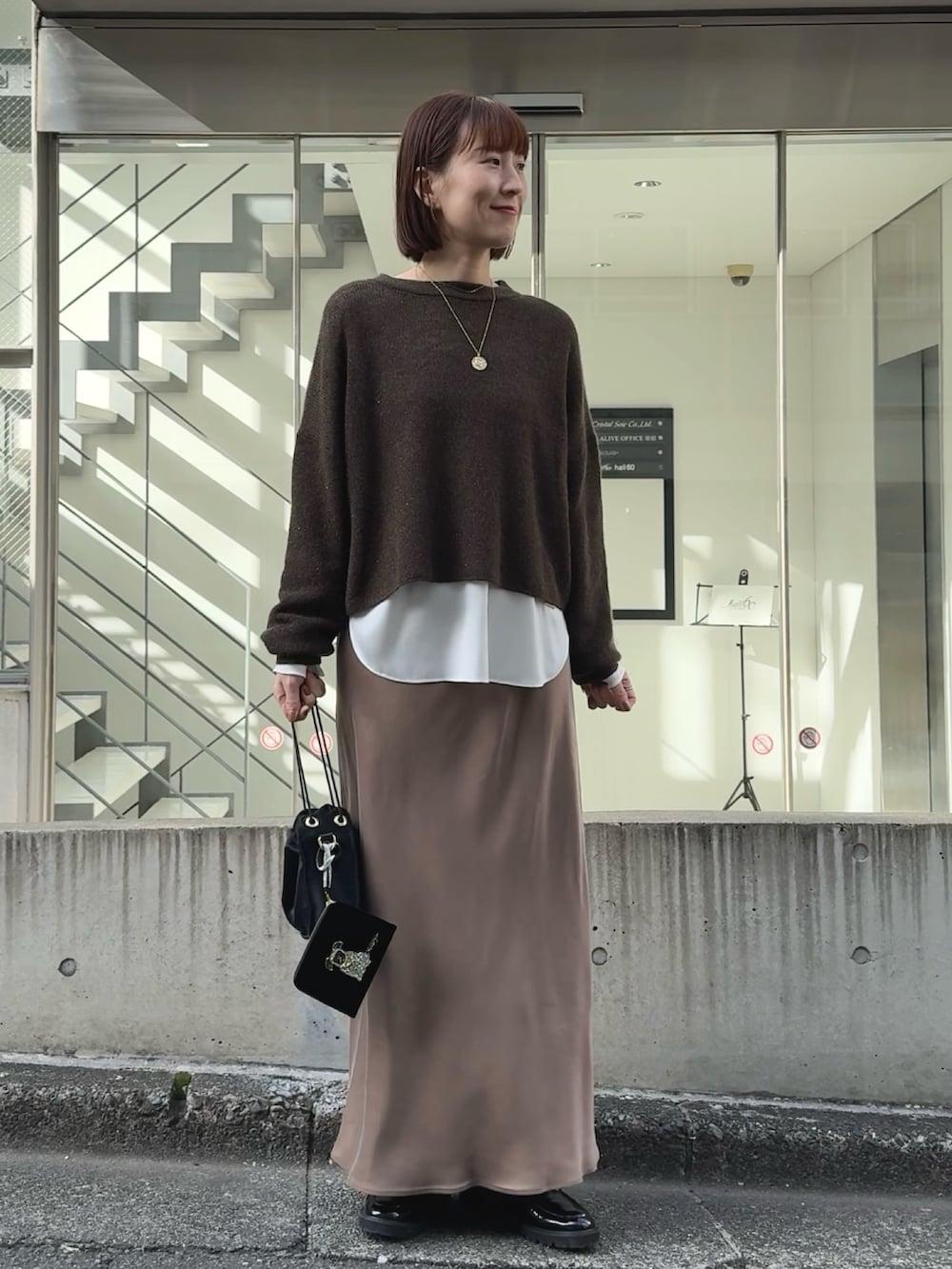 ホワイト系のシャツ/ブラウス、ブラウン系のニット/セーター、ブラック系のその他シューズを着用したレディースの冬コーディネートの2枚目の写真