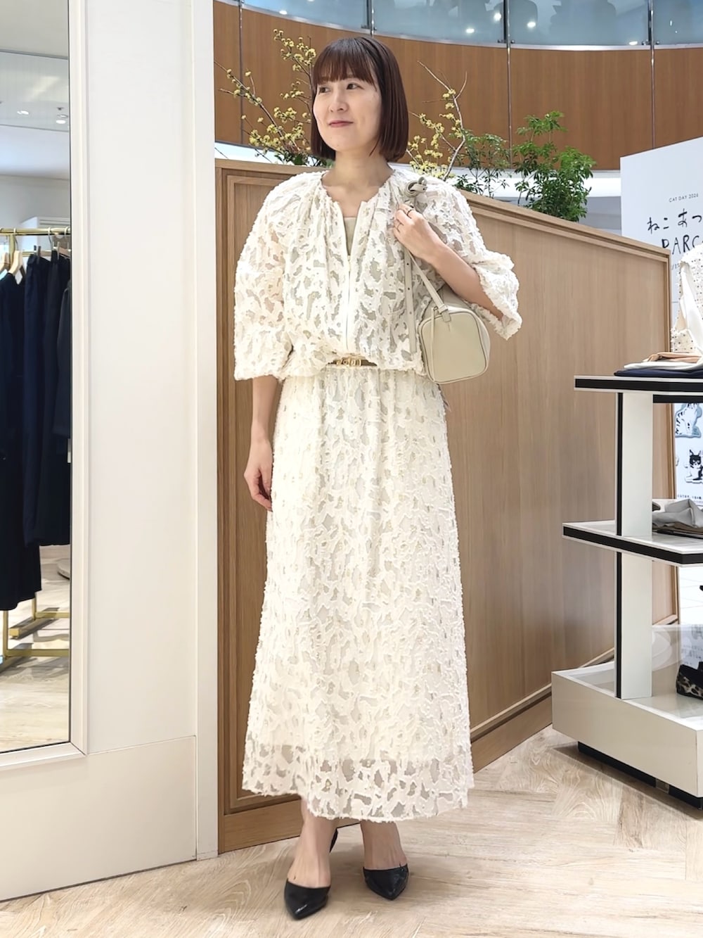 ホワイト系のショルダーバッグ、ゴールド系のタンクトップ、ホワイト系のブルゾンを着用したレディースの冬コーディネートの8枚目の写真