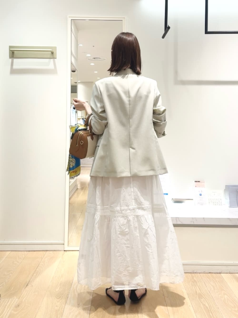 ベージュ系のテーラードジャケット、ベージュ系のタンクトップ、ブラウン系のボストンバッグを着用したレディースの春コーディネートの4枚目の写真