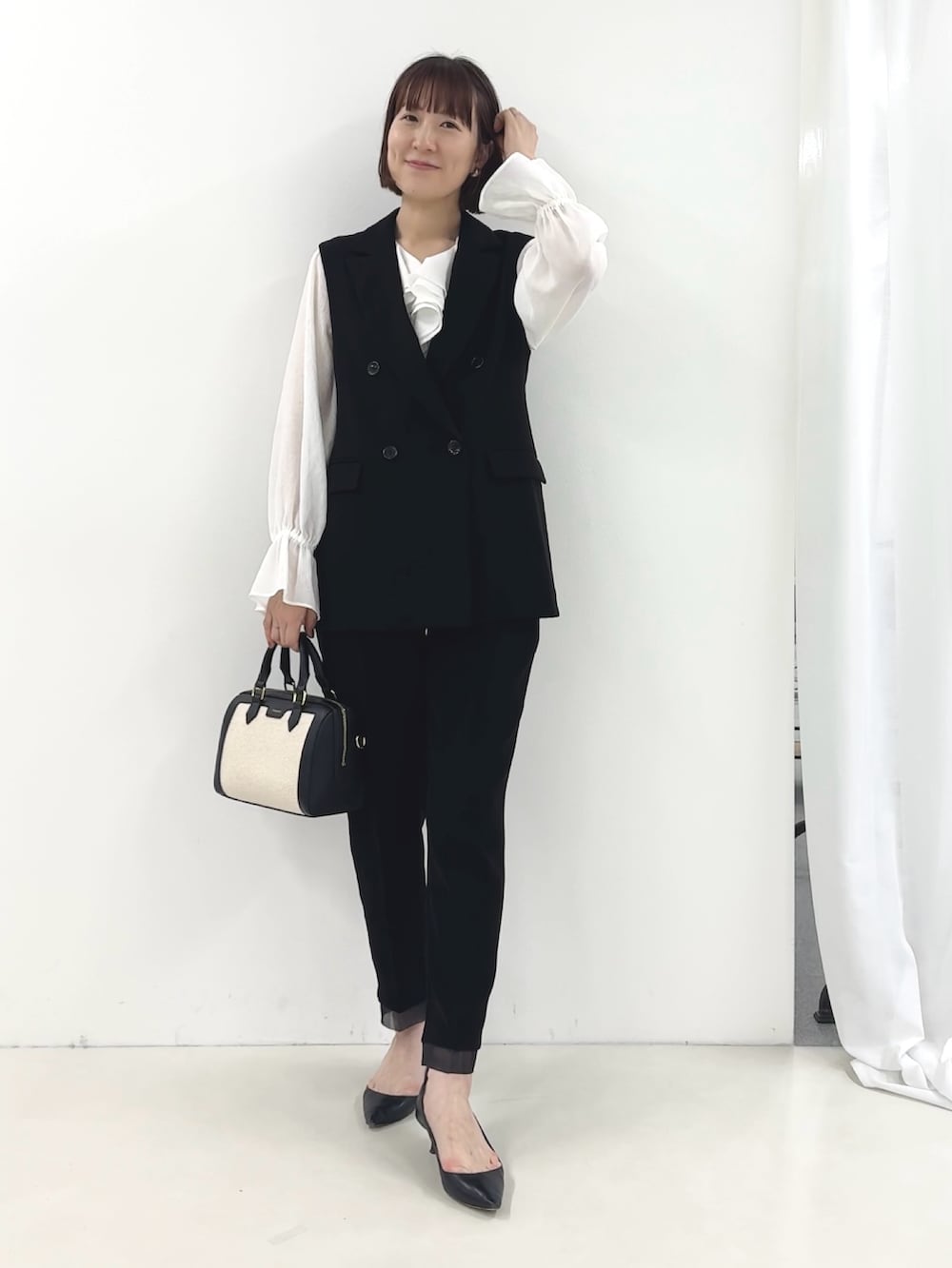 ブラック系のベスト、ホワイト系のシャツ/ブラウス、ブラック系のその他パンツを着用したレディースの冬コーディネートの2枚目の写真