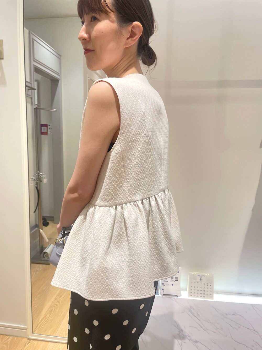 ホワイト系のベスト、ブラック系のその他パンツ、ブルー系のショルダーバッグを着用したレディースの夏コーディネートの4枚目の写真