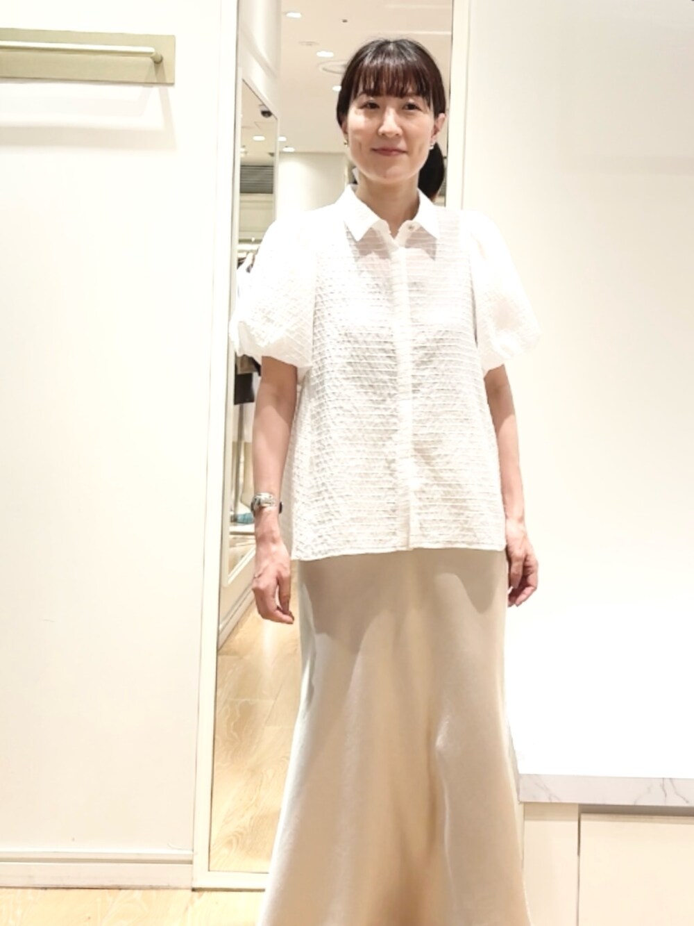 ベージュ系のスカート、ホワイト系のシャツ/ブラウス、ゴールド系のバレッタ/ヘアクリップを着用したレディースの夏コーディネートの6枚目の写真