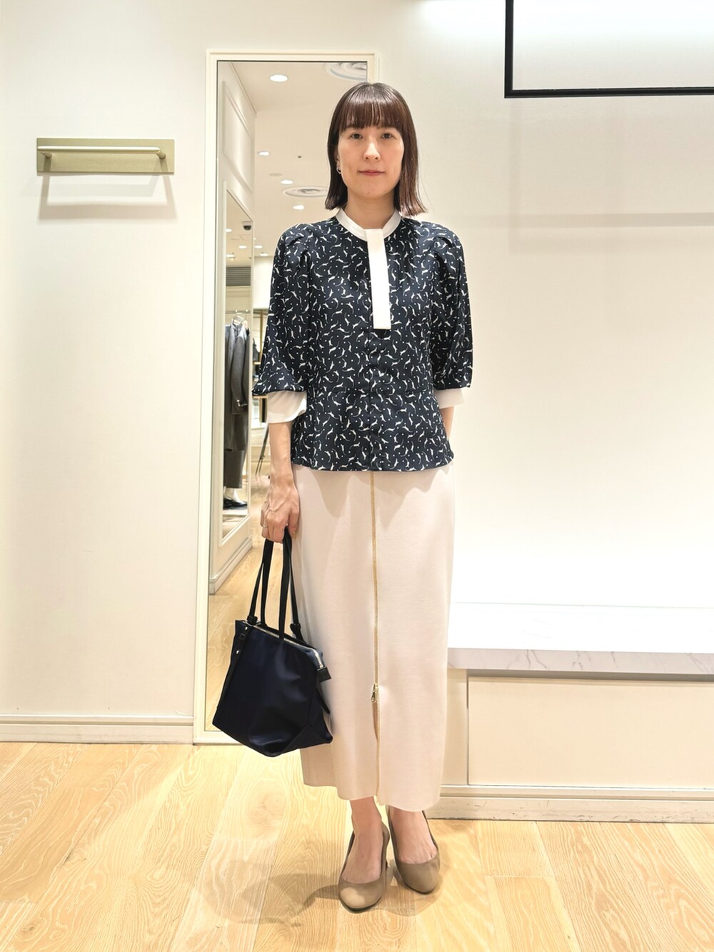 ベージュ系のスカート、ブルー系のトートバッグ、ブルー系のシャツ/ブラウスを着用したレディースの秋コーディネートの3枚目の写真