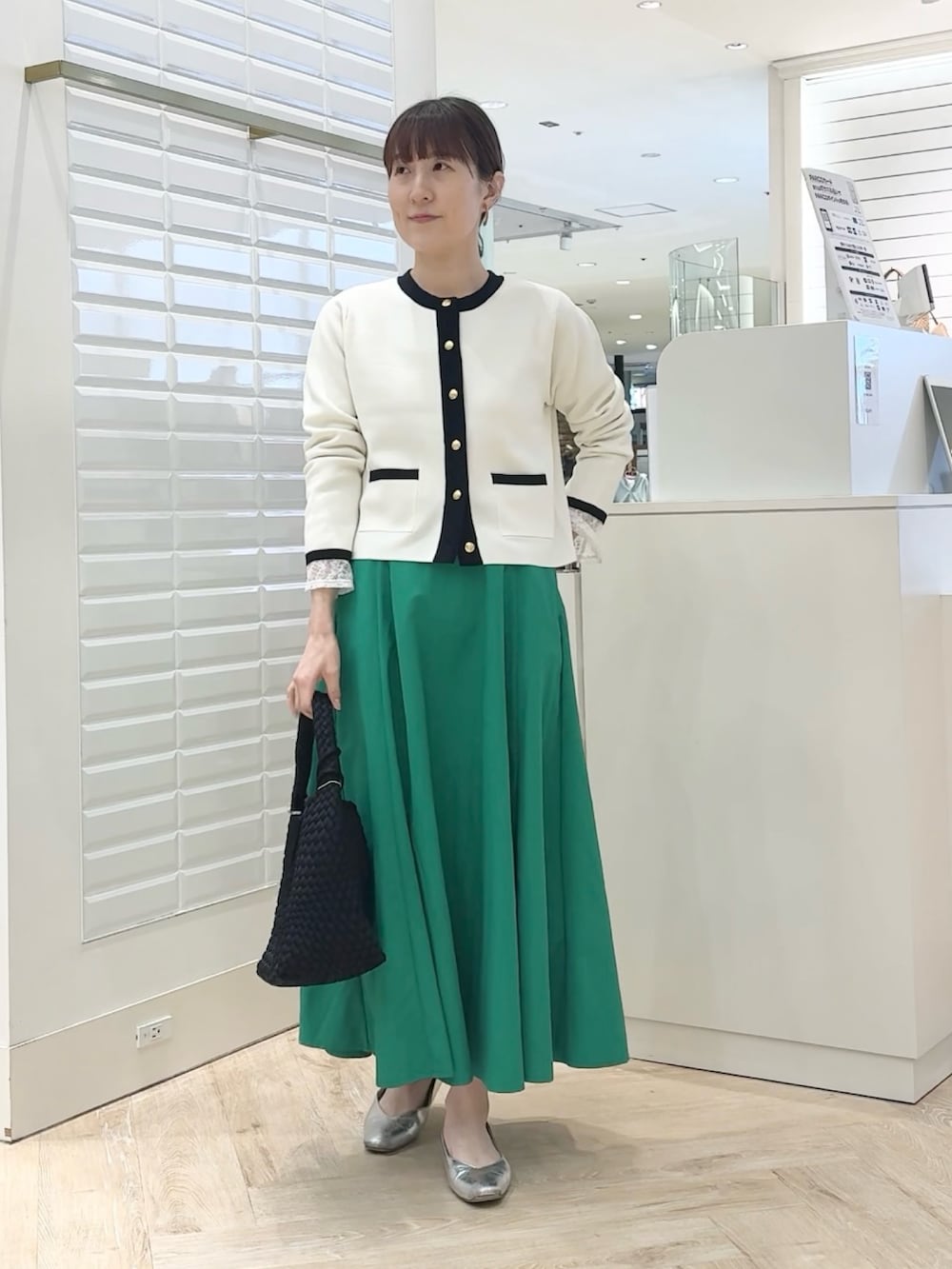 ホワイト系のカーディガン/ボレロ、グリーン系のスカート、ブラック系のショルダーバッグを着用したレディースの春コーディネートの8枚目の写真