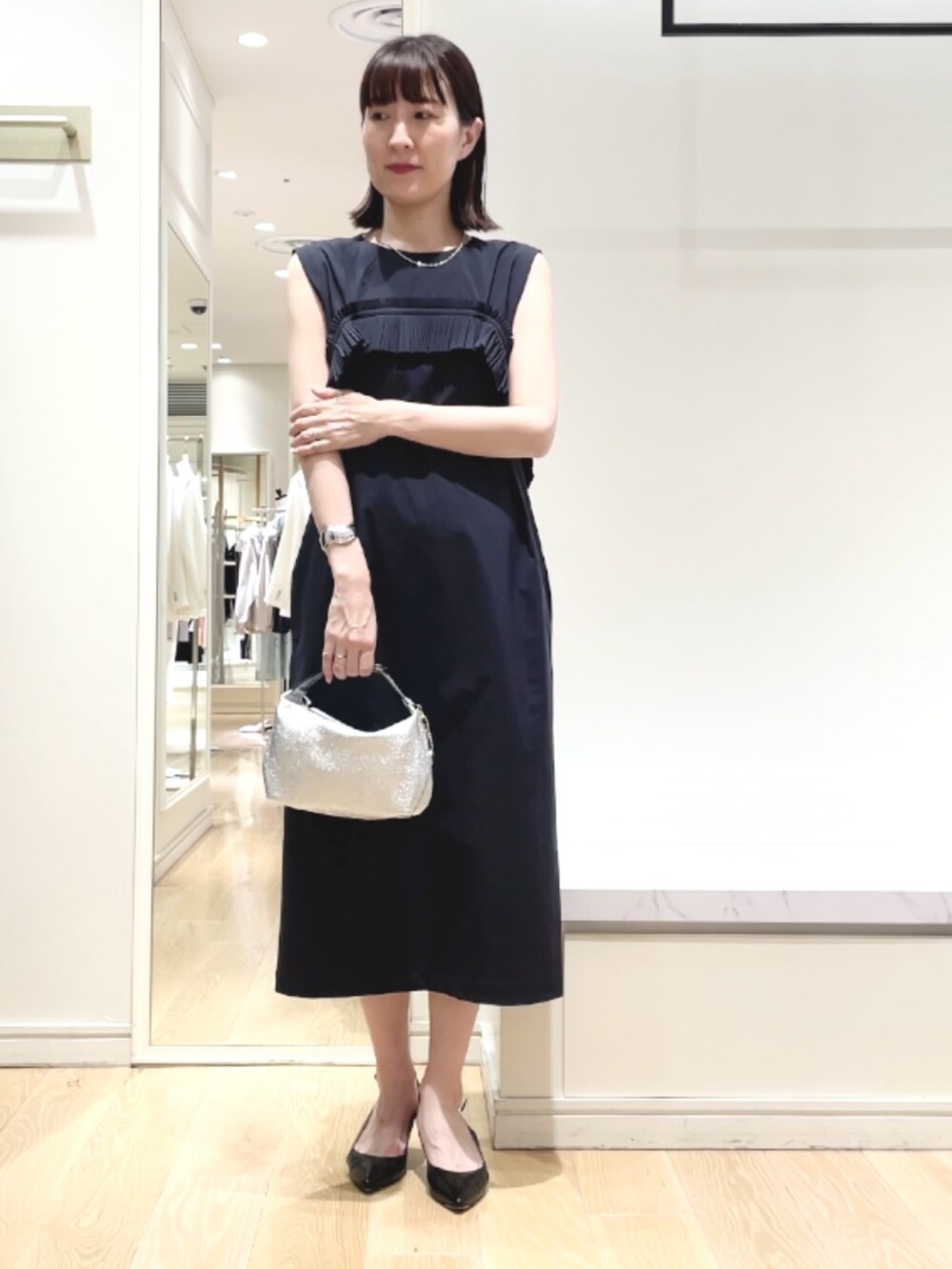 ブラック系のパンプス、ブルー系のワンピース、シルバー系のネックレスを着用したレディースの春コーディネートの8枚目の写真