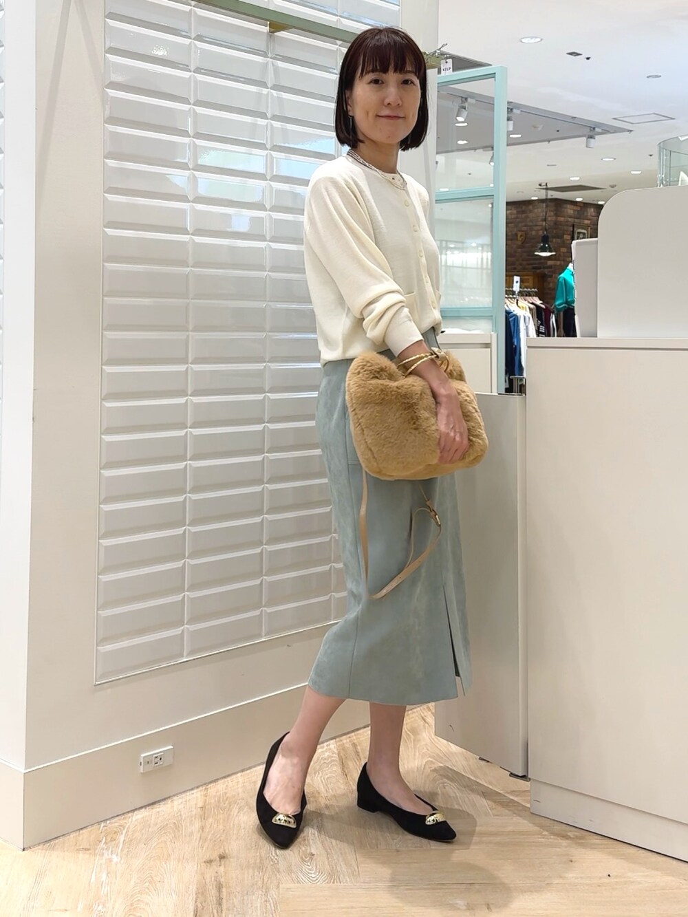 ホワイト系のカーディガン/ボレロ、ベージュ系のショルダーバッグ、グリーン系のスカートを着用したレディースの秋コーディネートの5枚目の写真