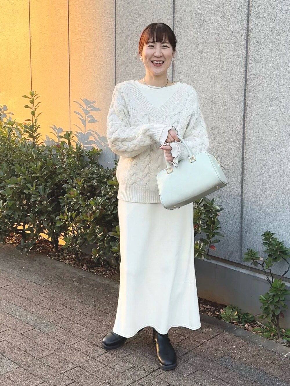 ホワイト系のニット/セーター、ホワイト系のTシャツ/カットソー、グリーン系のショルダーバッグを着用したレディースの冬コーディネートの7枚目の写真