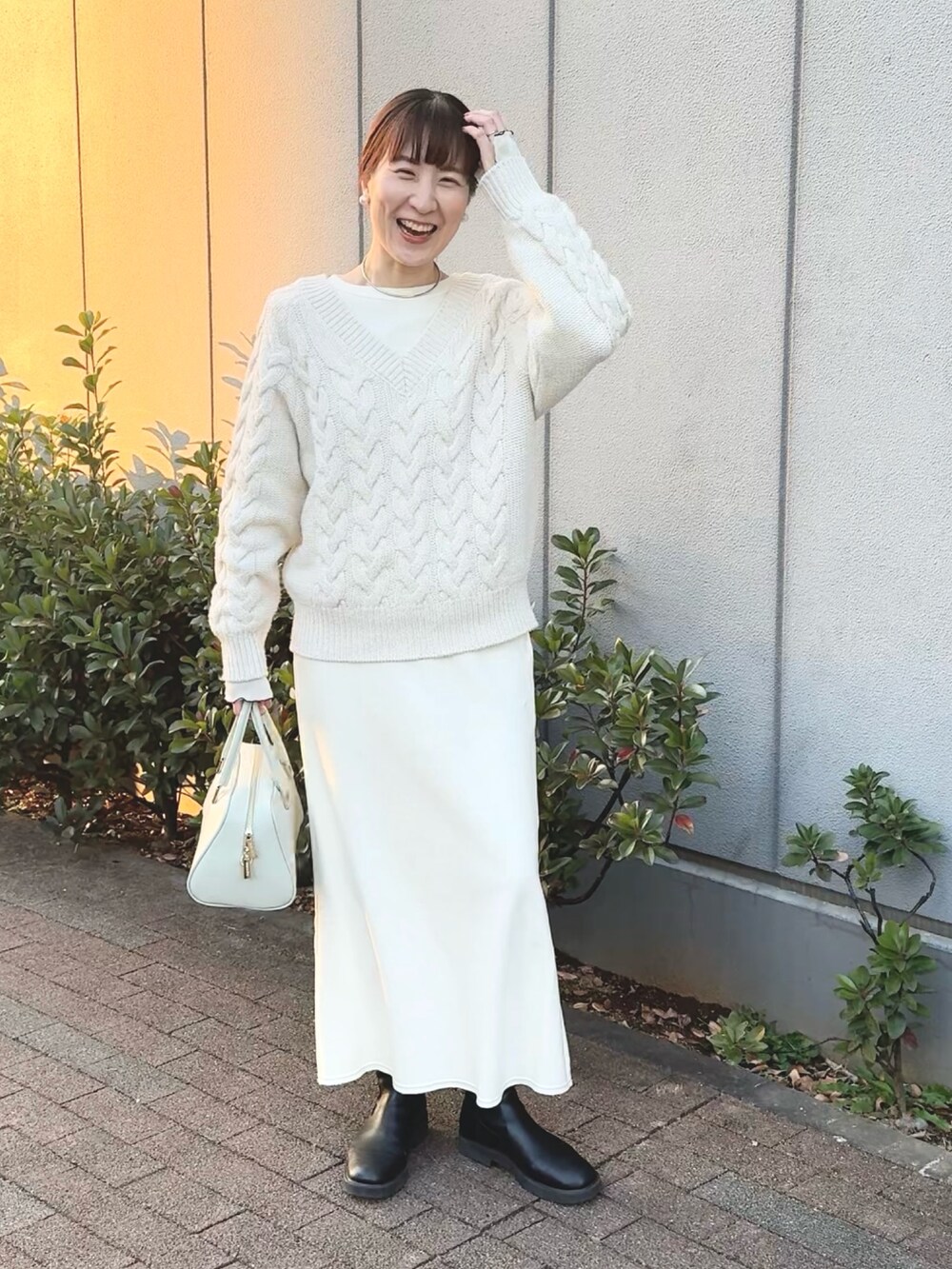 ホワイト系のニット/セーター、ホワイト系のTシャツ/カットソー、グリーン系のショルダーバッグを着用したレディースの冬コーディネートの5枚目の写真