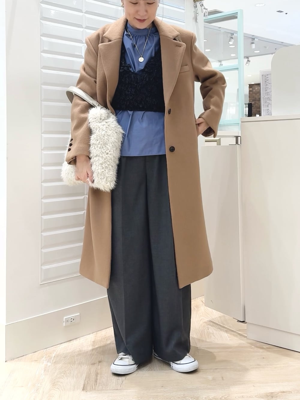 グレー系のベスト、ブルー系のシャツ/ブラウス、ホワイト系のショルダーバッグを着用したレディースの秋コーディネートの4枚目の写真