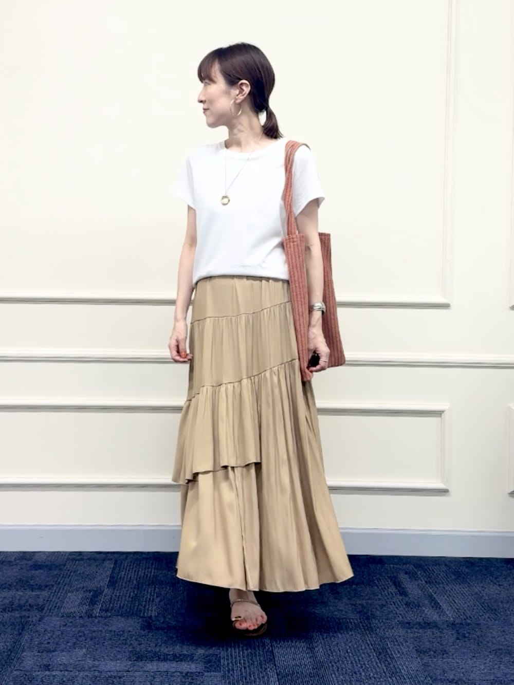 レッド系のトートバッグ、イエロー系のスカート、ホワイト系のTシャツ/カットソーを着用したレディースの夏コーディネートの2枚目の写真