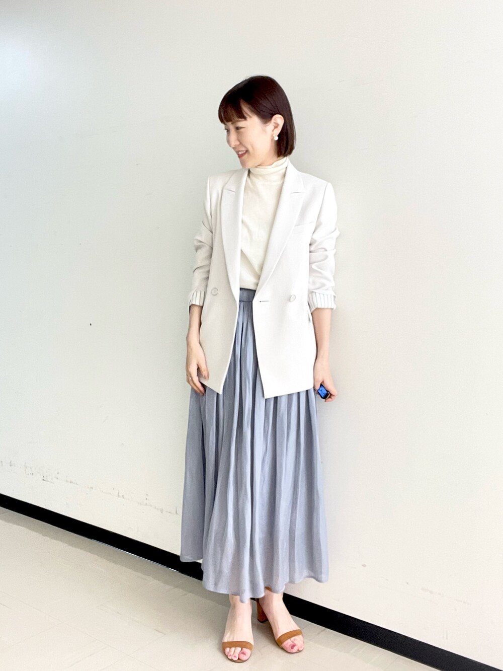 ホワイト系のニット/セーター、ベージュ系のテーラードジャケット、ゴールド系のイヤリングを着用したレディースの冬コーディネートの2枚目の写真