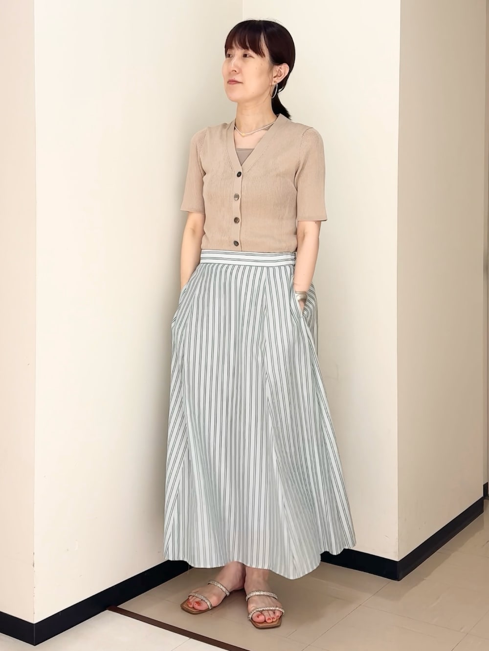 ブルー系のスカート、ベージュ系のカーディガン/ボレロ、ベージュ系のタンクトップを着用したレディースの夏コーディネートの9枚目の写真