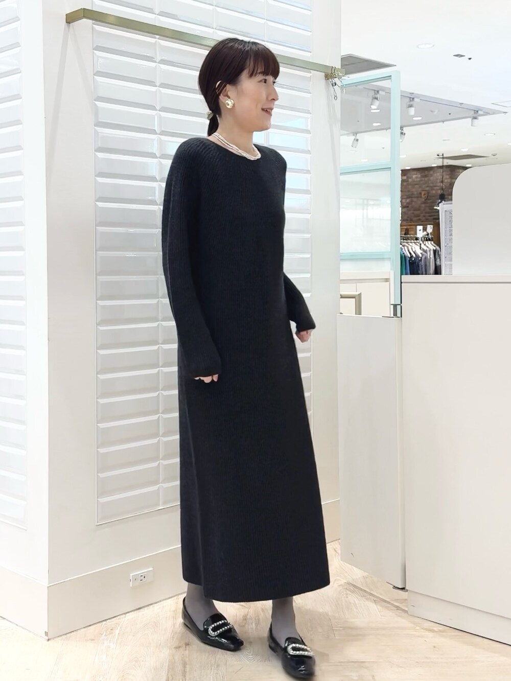 グレー系のワンピース、ゴールド系のイヤリング、ホワイト系のネックレスを着用したレディースの冬コーディネートの7枚目の写真