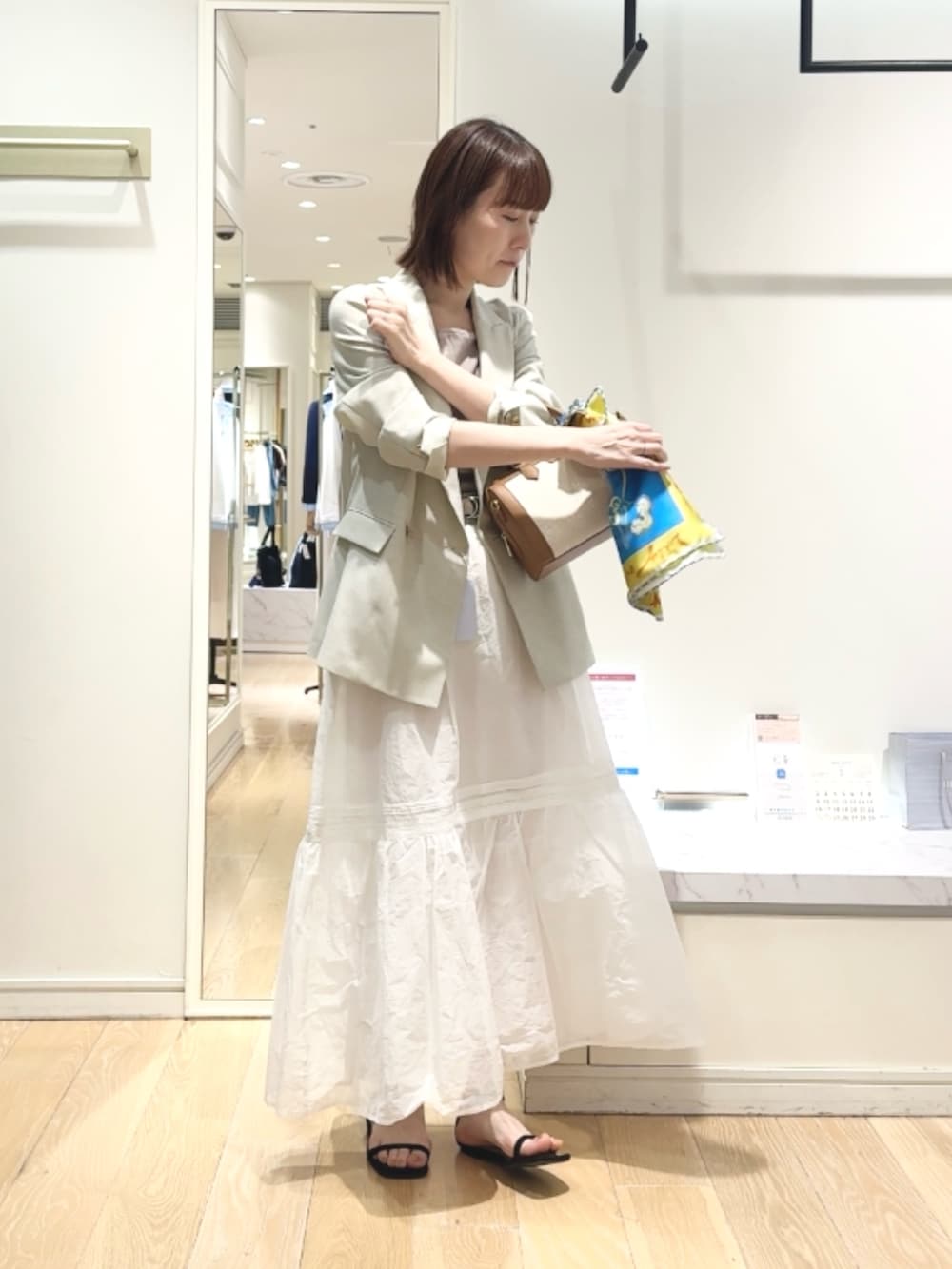 ベージュ系のテーラードジャケット、ベージュ系のタンクトップ、ブラウン系のボストンバッグを着用したレディースの春コーディネートの2枚目の写真