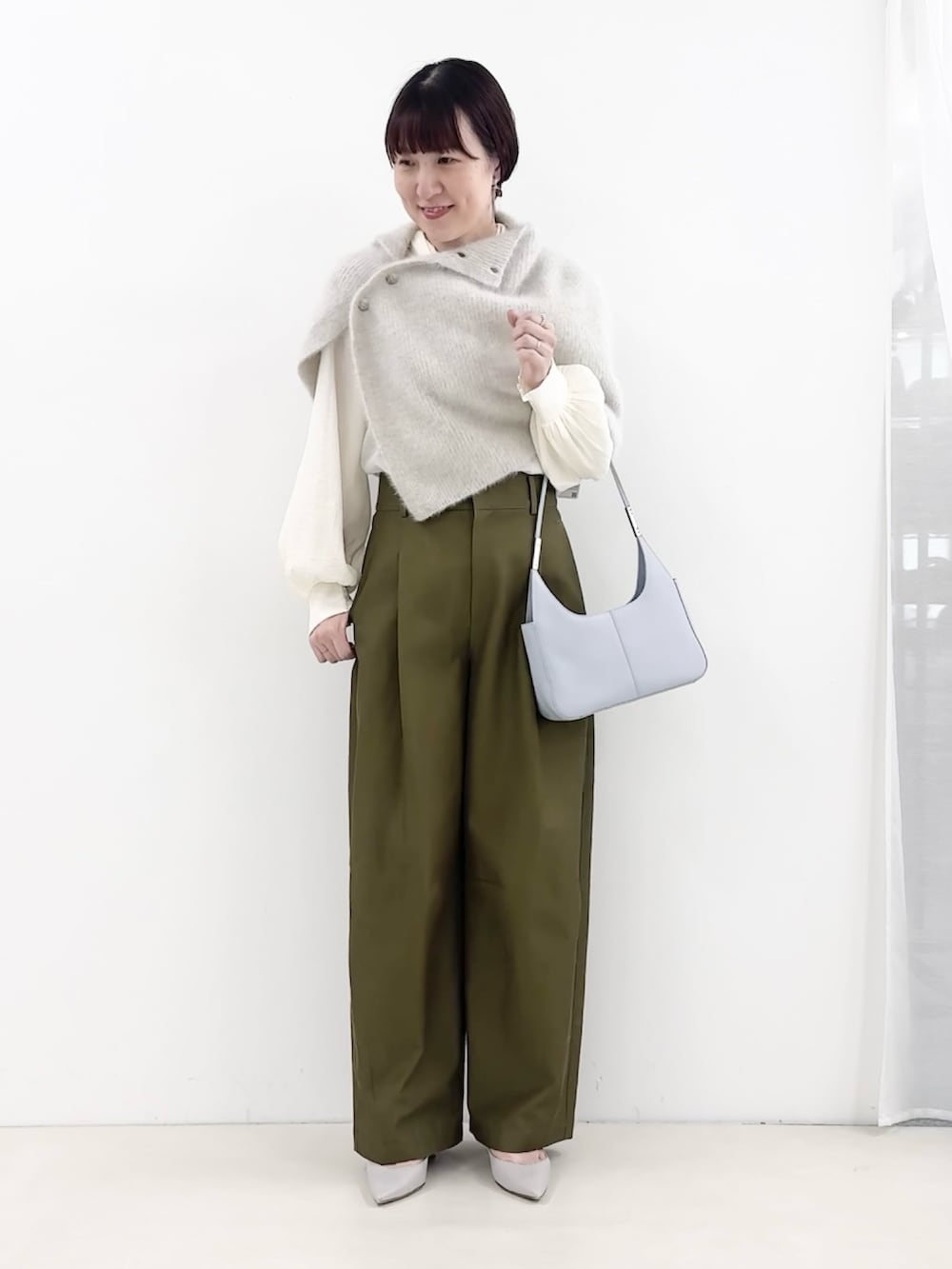 ブルー系のショルダーバッグ、グリーン系のチノパンツ、ホワイト系のシャツ/ブラウスを着用したレディースの秋コーディネートの5枚目の写真