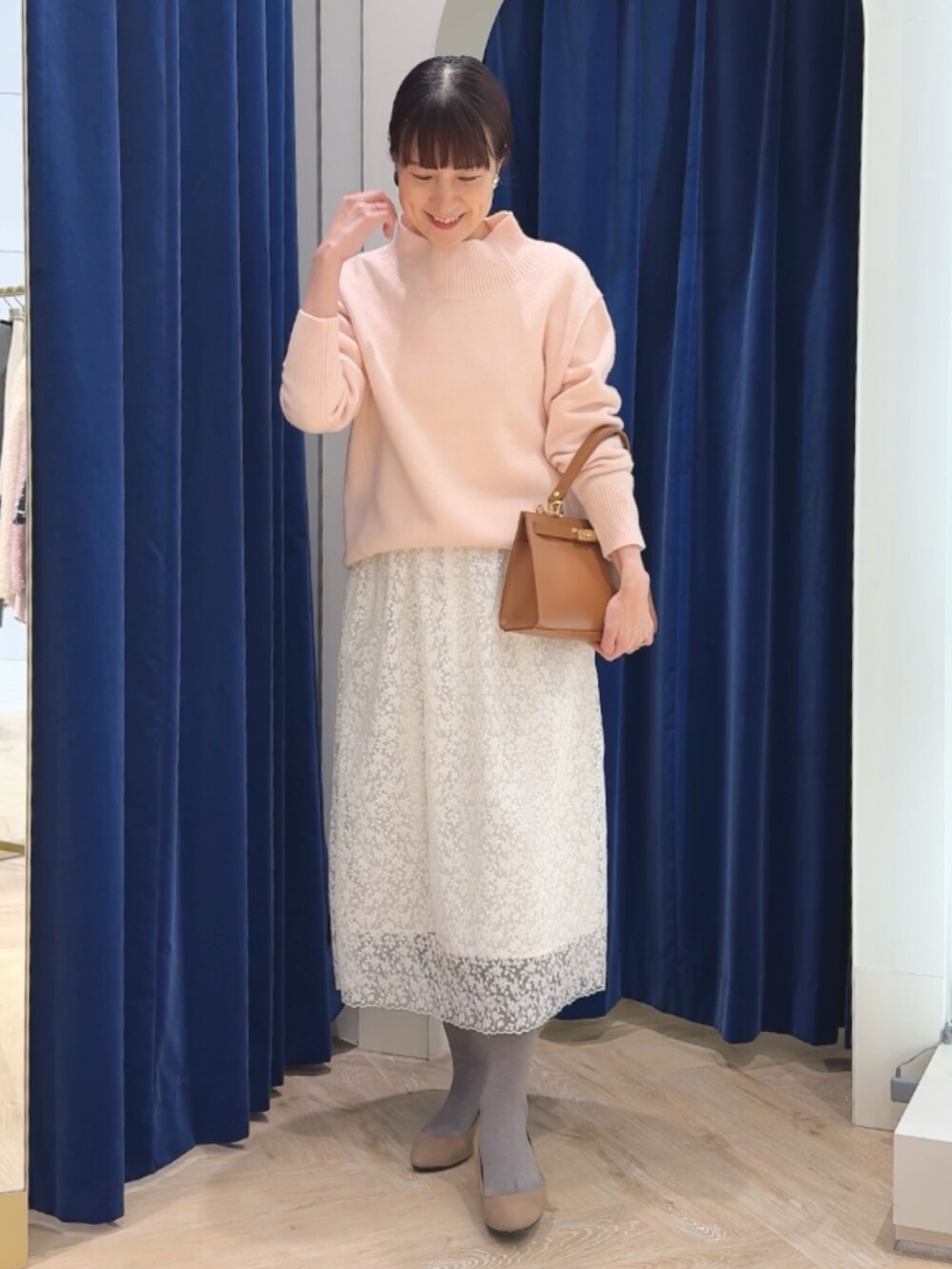 ピンク系のニット/セーター、イエロー系のショルダーバッグ、ホワイト系のスカートを着用したレディースの冬コーディネートの9枚目の写真