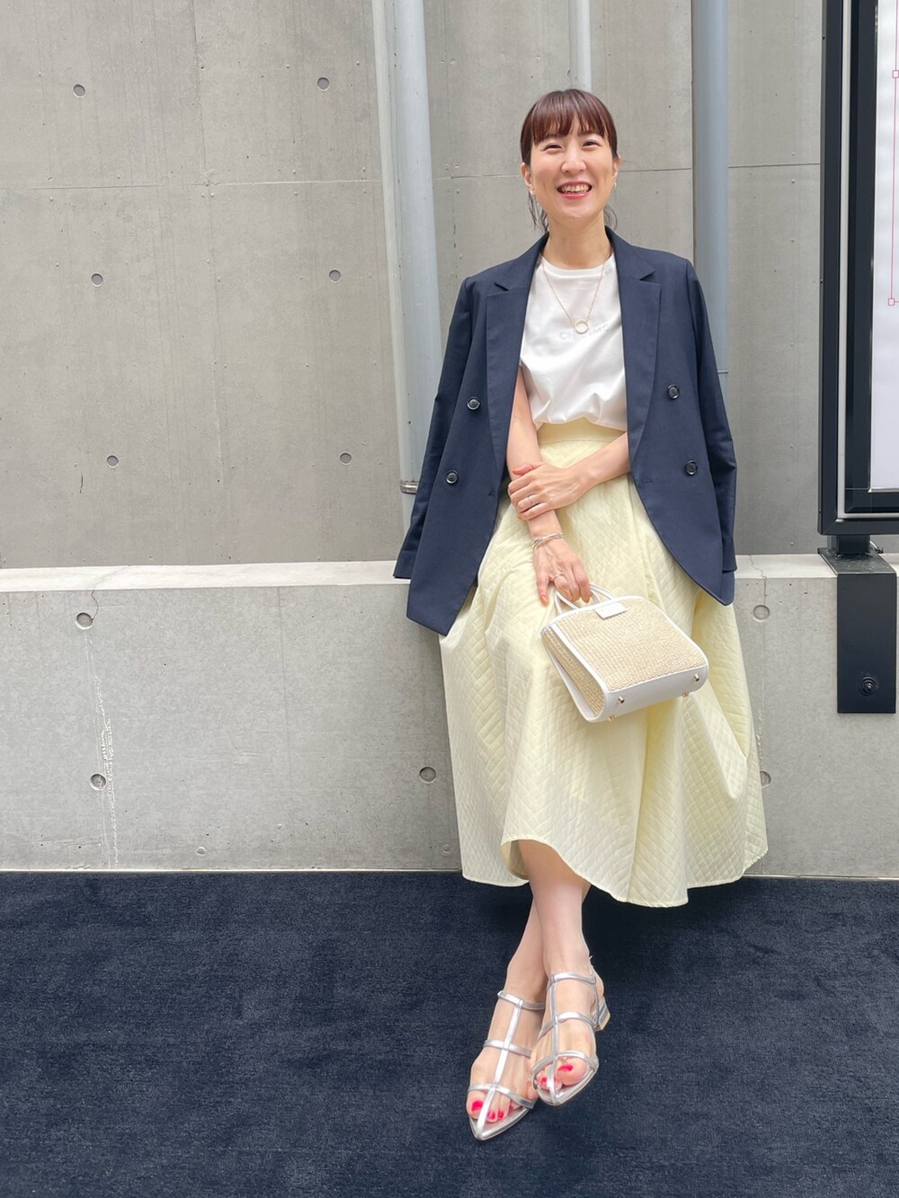 ブルー系のテーラードジャケット、ホワイト系のトートバッグ、イエロー系のスカートを着用したレディースの春コーディネートの4枚目の写真