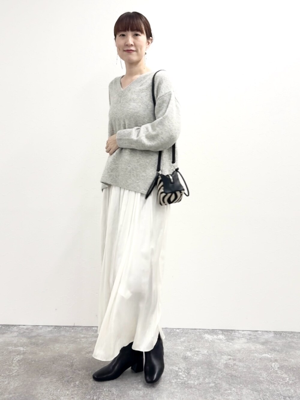 グレー系のニット/セーター、ブルー系のショルダーバッグ、ホワイト系のスカートを着用したレディースの冬コーディネートの7枚目の写真