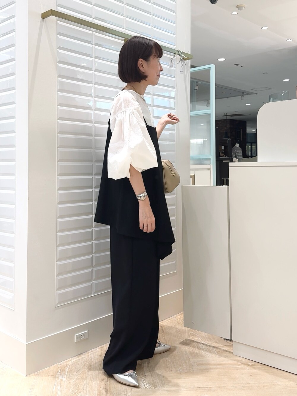 ブラック系のその他パンツ、ホワイト系のシャツ/ブラウス、ベージュ系のショルダーバッグを着用したレディースの秋コーディネートの2枚目の写真