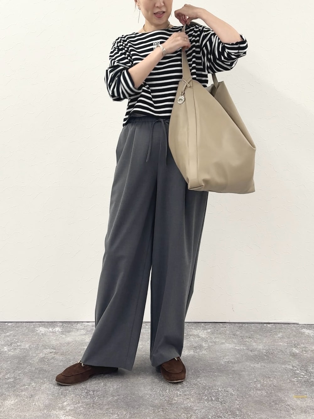 ブラック系のTシャツ/カットソー、ベージュ系のショルダーバッグ、グレー系のその他パンツを着用したレディースの秋コーディネートの7枚目の写真