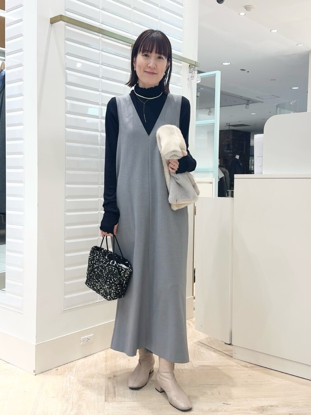 グレー系のワンピース、ブラック系のショルダーバッグ、ブルー系のTシャツ/カットソーを着用したレディースの冬コーディネートの7枚目の写真