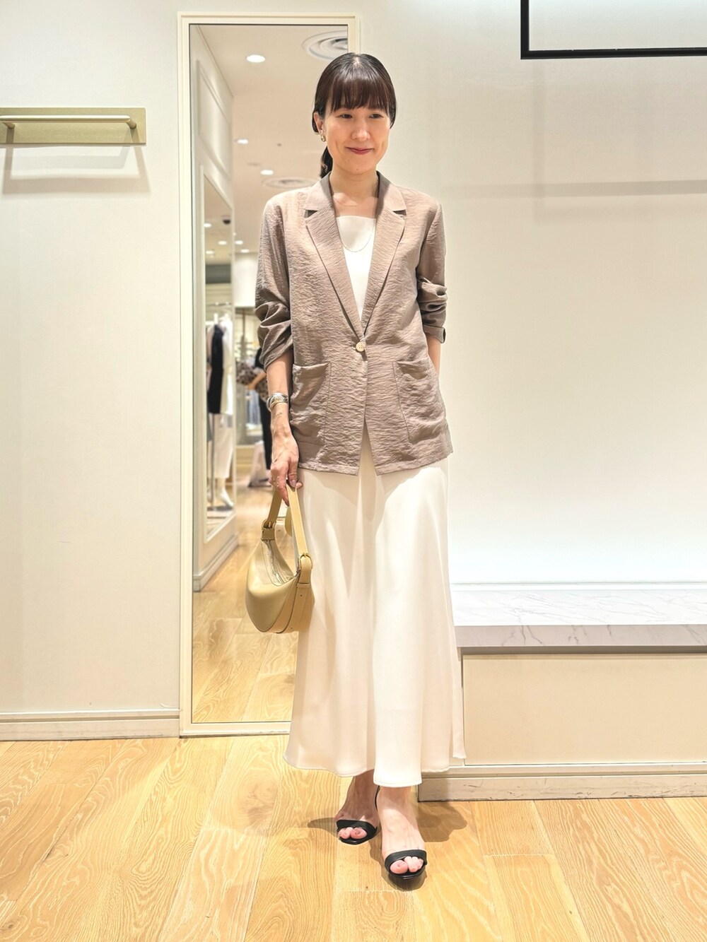 グリーン系のテーラードジャケット、ホワイト系のタンクトップ、ホワイト系のスカートを着用したレディースの夏コーディネートの10枚目の写真