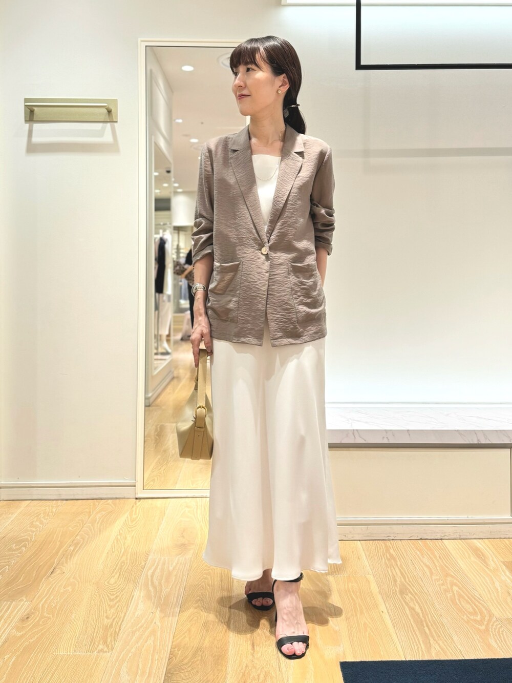 グリーン系のテーラードジャケット、ホワイト系のタンクトップ、ホワイト系のスカートを着用したレディースの夏コーディネートの2枚目の写真