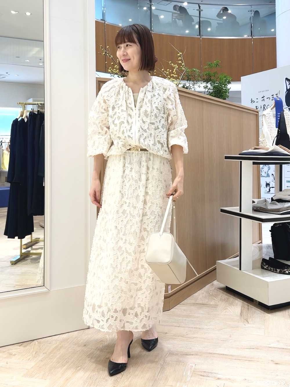 ホワイト系のショルダーバッグ、ゴールド系のタンクトップ、ホワイト系のブルゾンを着用したレディースの冬コーディネートの3枚目の写真