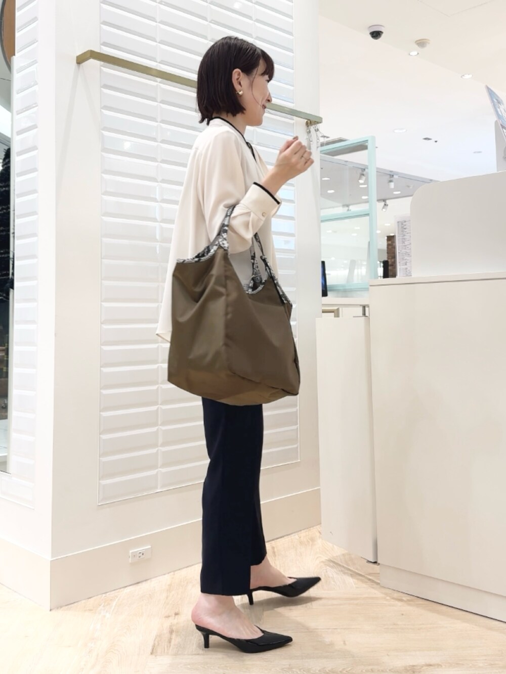 ブルー系のその他パンツ、ブラウン系のトートバッグ、ホワイト系のシャツ/ブラウスを着用したレディースの秋コーディネートの2枚目の写真
