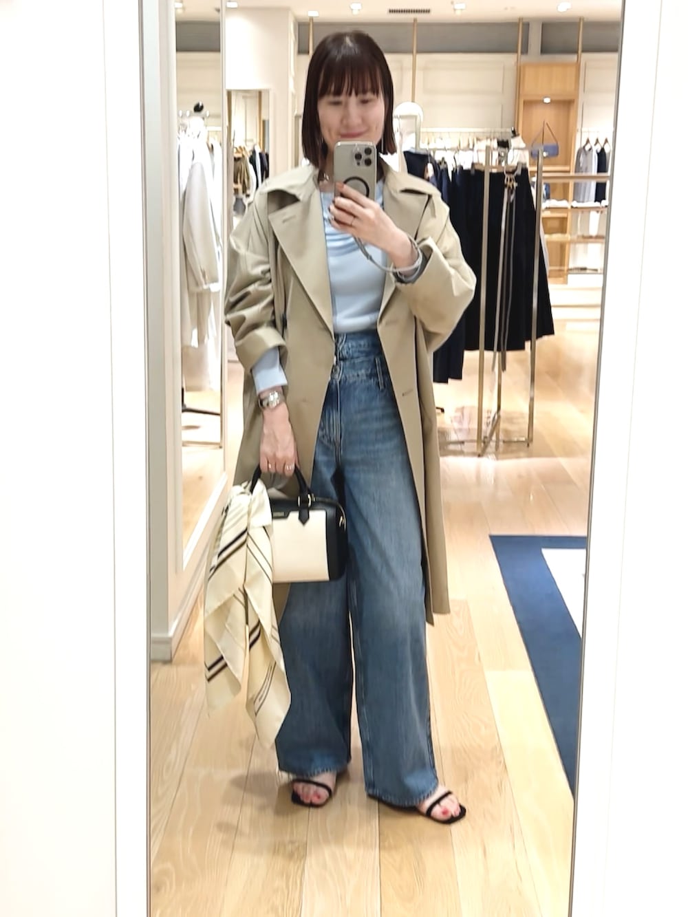 ブラック系のボストンバッグ、ブルー系のニット/セーター、ベージュ系のトレンチコートを着用したレディースの春コーディネートの10枚目の写真