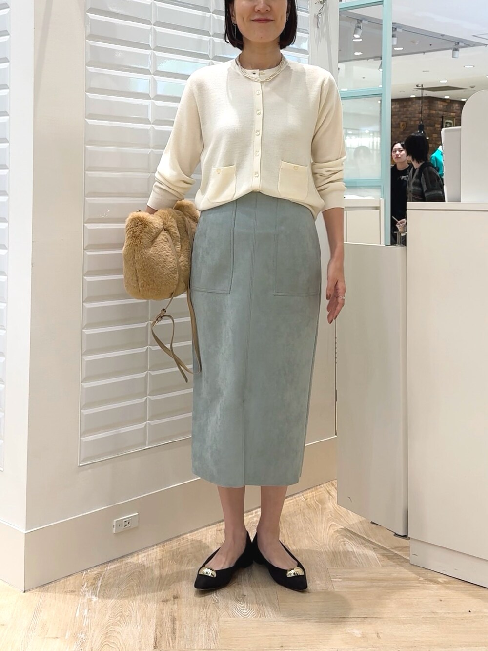 ホワイト系のカーディガン/ボレロ、ベージュ系のショルダーバッグ、グリーン系のスカートを着用したレディースの秋コーディネートの2枚目の写真