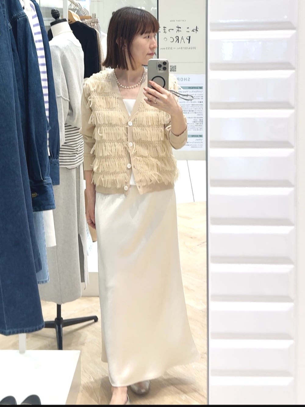 ホワイト系のスカート、ホワイト系のタンクトップ、ベージュ系のカーディガン/ボレロを着用したレディースの春コーディネートの2枚目の写真