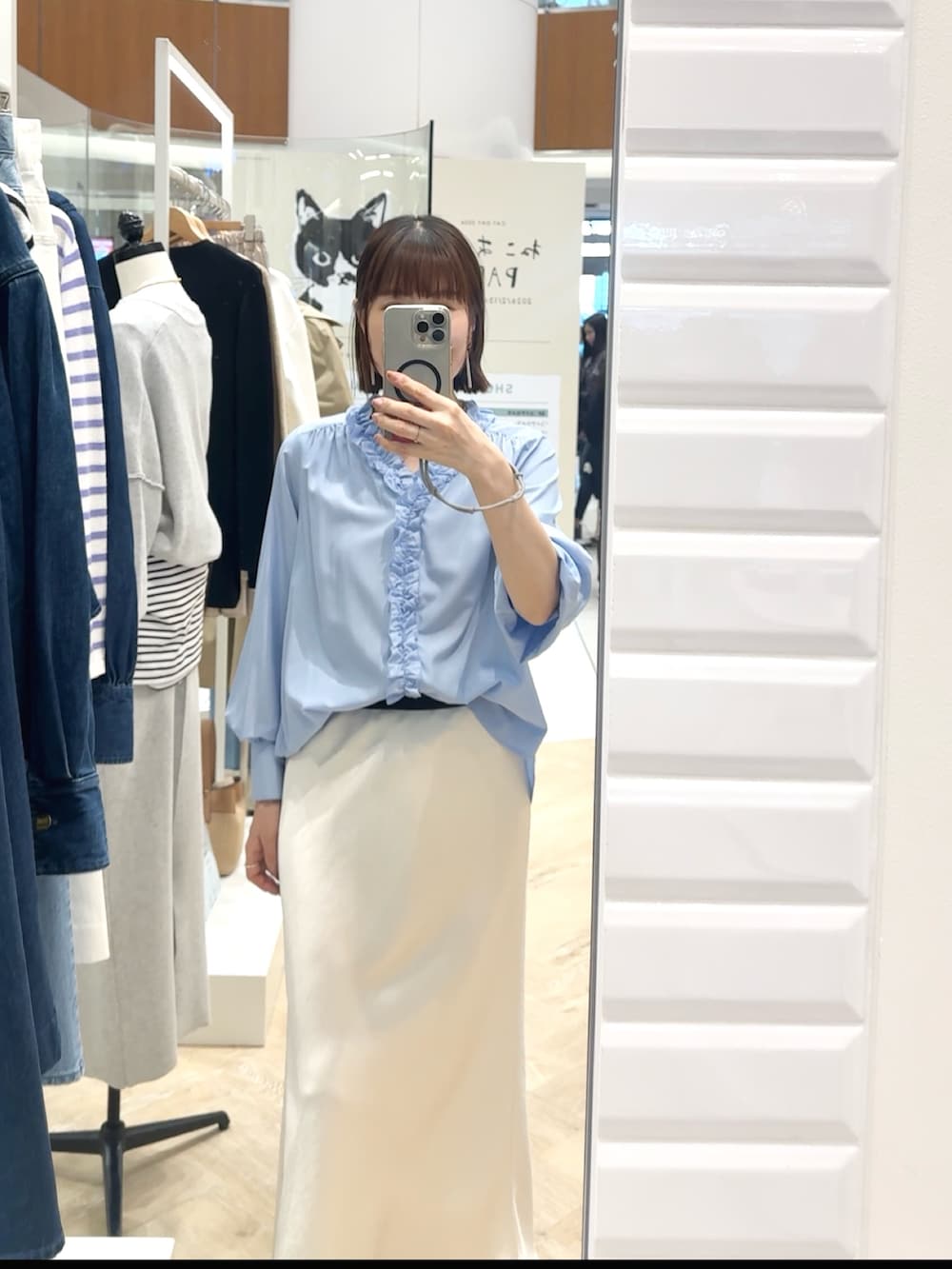 ブルー系のシャツ/ブラウス、ホワイト系のスカート、グレー系のネックレスを着用したレディースの春コーディネートの4枚目の写真