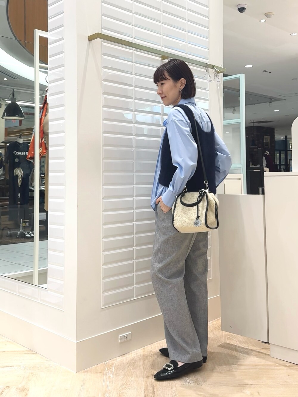 ホワイト系のボストンバッグ、ブルー系のベスト、ブルー系のシャツ/ブラウスを着用したレディースの秋コーディネートの7枚目の写真
