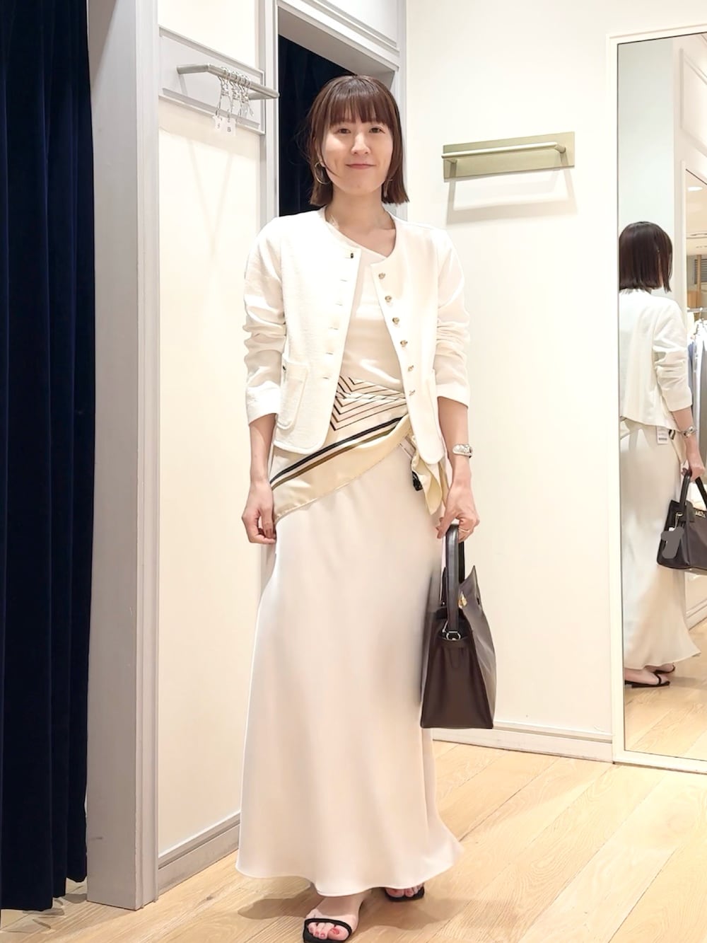 ホワイト系のタンクトップ、ホワイト系のノーカラージャケット、ホワイト系のスカートを着用したレディースの春コーディネートの9枚目の写真