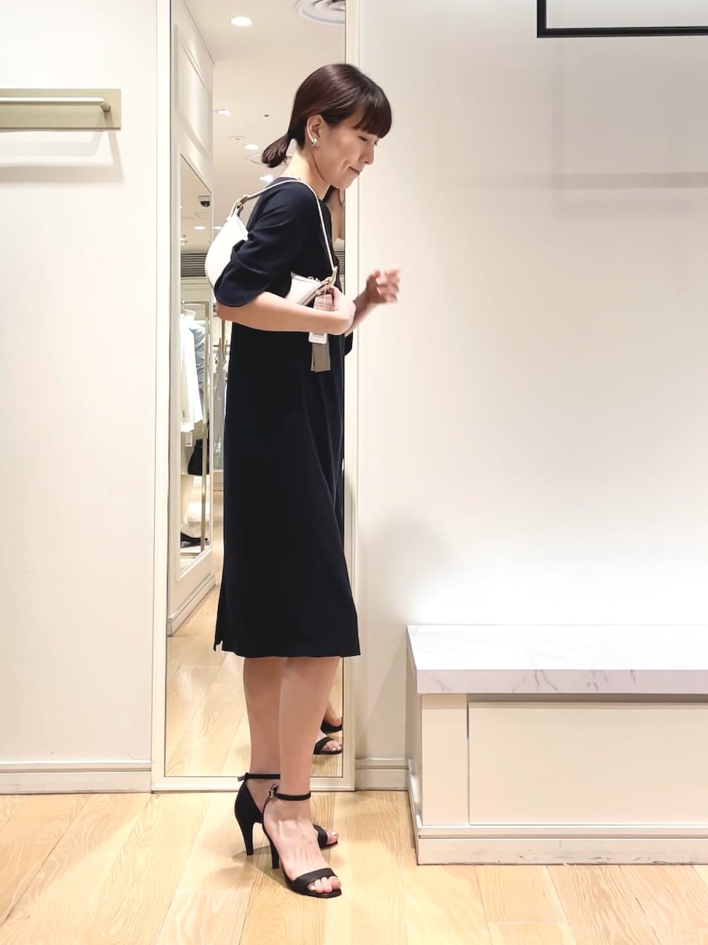 ブルー系のワンピース、ホワイト系のショルダーバッグ、シルバー系のイヤリングを着用したレディースの春コーディネートの3枚目の写真