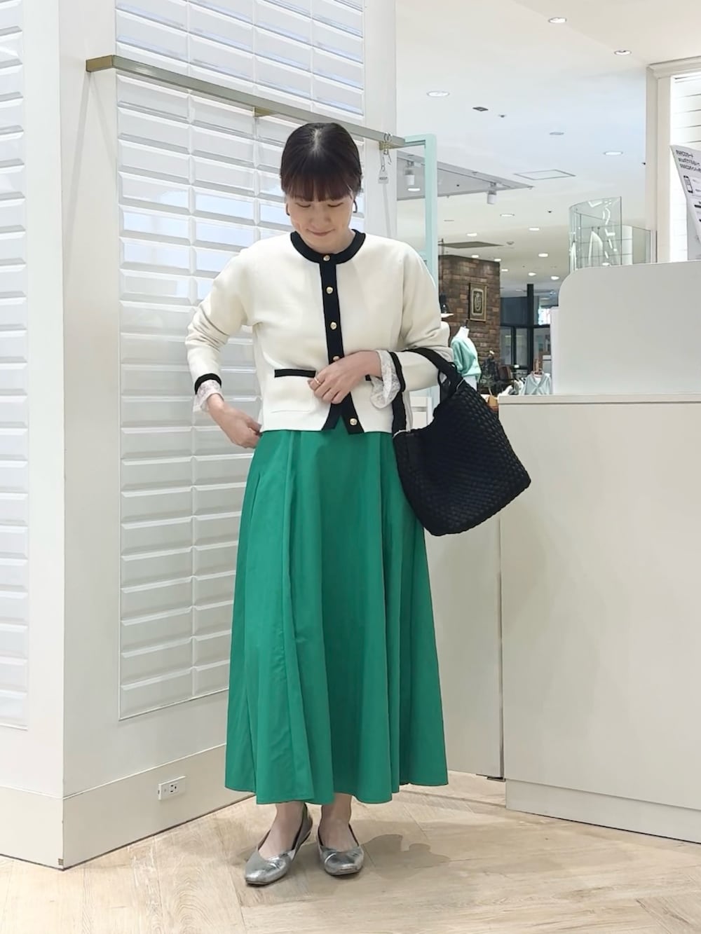 ホワイト系のカーディガン/ボレロ、グリーン系のスカート、ブラック系のショルダーバッグを着用したレディースの春コーディネートの4枚目の写真