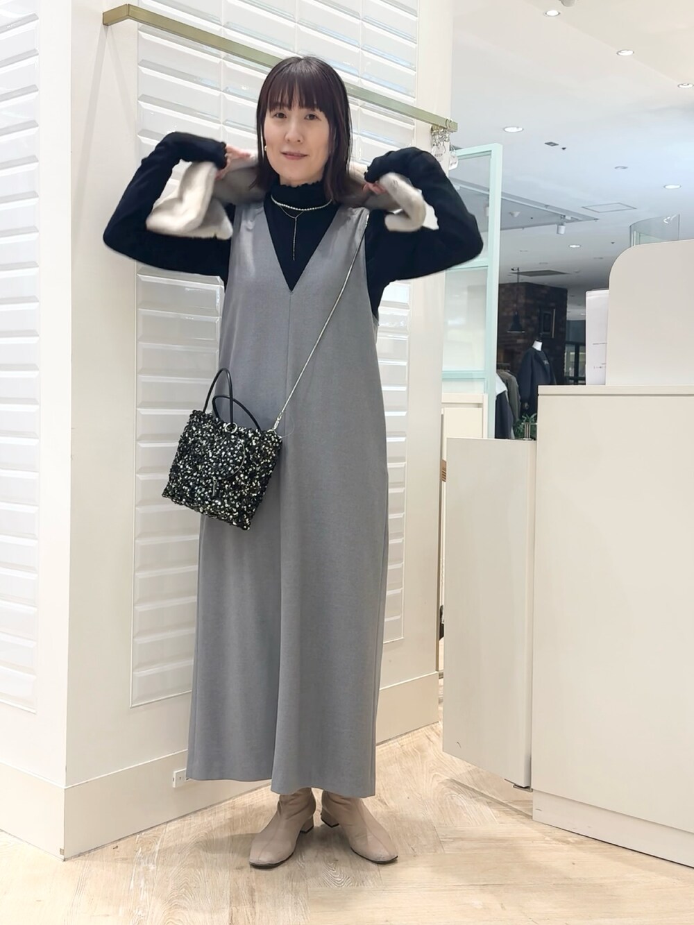 グレー系のワンピース、ブラック系のショルダーバッグ、ブルー系のTシャツ/カットソーを着用したレディースの冬コーディネートの6枚目の写真