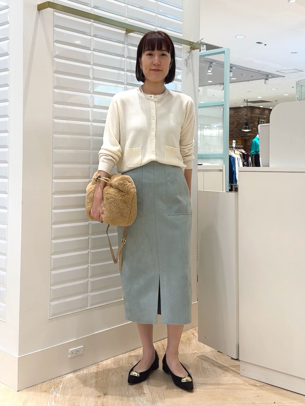 ホワイト系のカーディガン/ボレロ、ベージュ系のショルダーバッグ、グリーン系のスカートを着用したレディースの秋コーディネートの7枚目の写真
