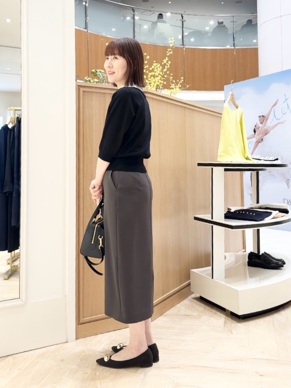 ブラック系のボストンバッグ、ブラック系のニット/セーター、グレー系のスカートを着用したレディースの春コーディネートの8枚目の写真