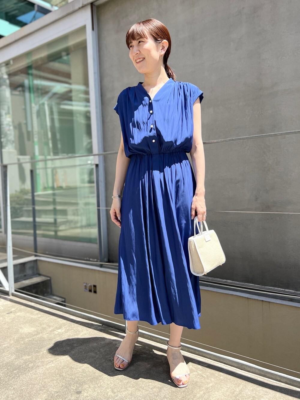 ホワイト系のトートバッグ、ブルー系のワンピース、ホワイト系のサンダルを着用したレディースの春コーディネートの5枚目の写真