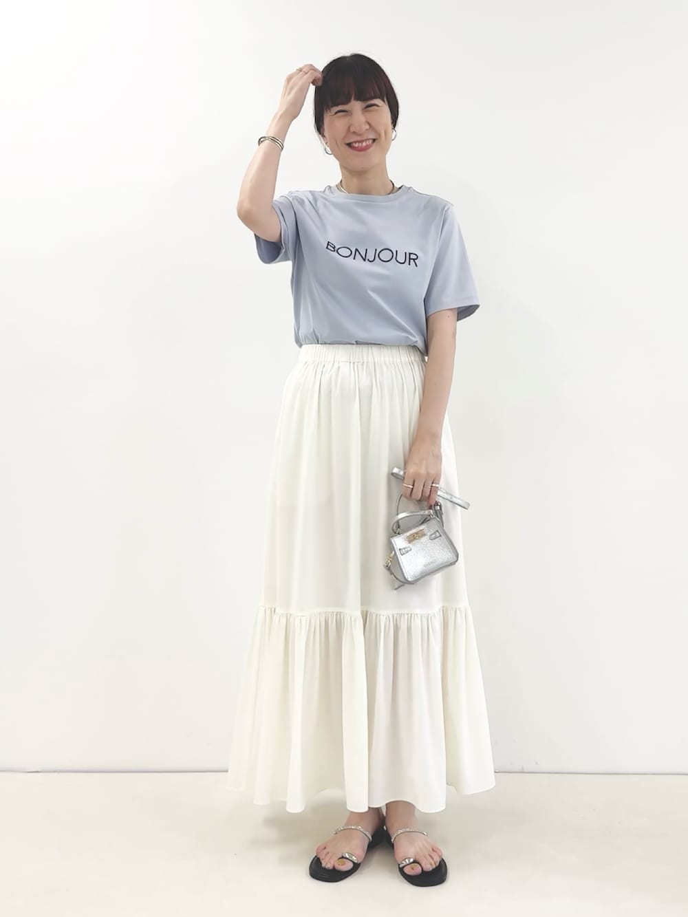 ホワイト系のスカート、シルバー系のサンダル、ブルー系のTシャツ/カットソーを着用したレディースの夏コーディネートの2枚目の写真