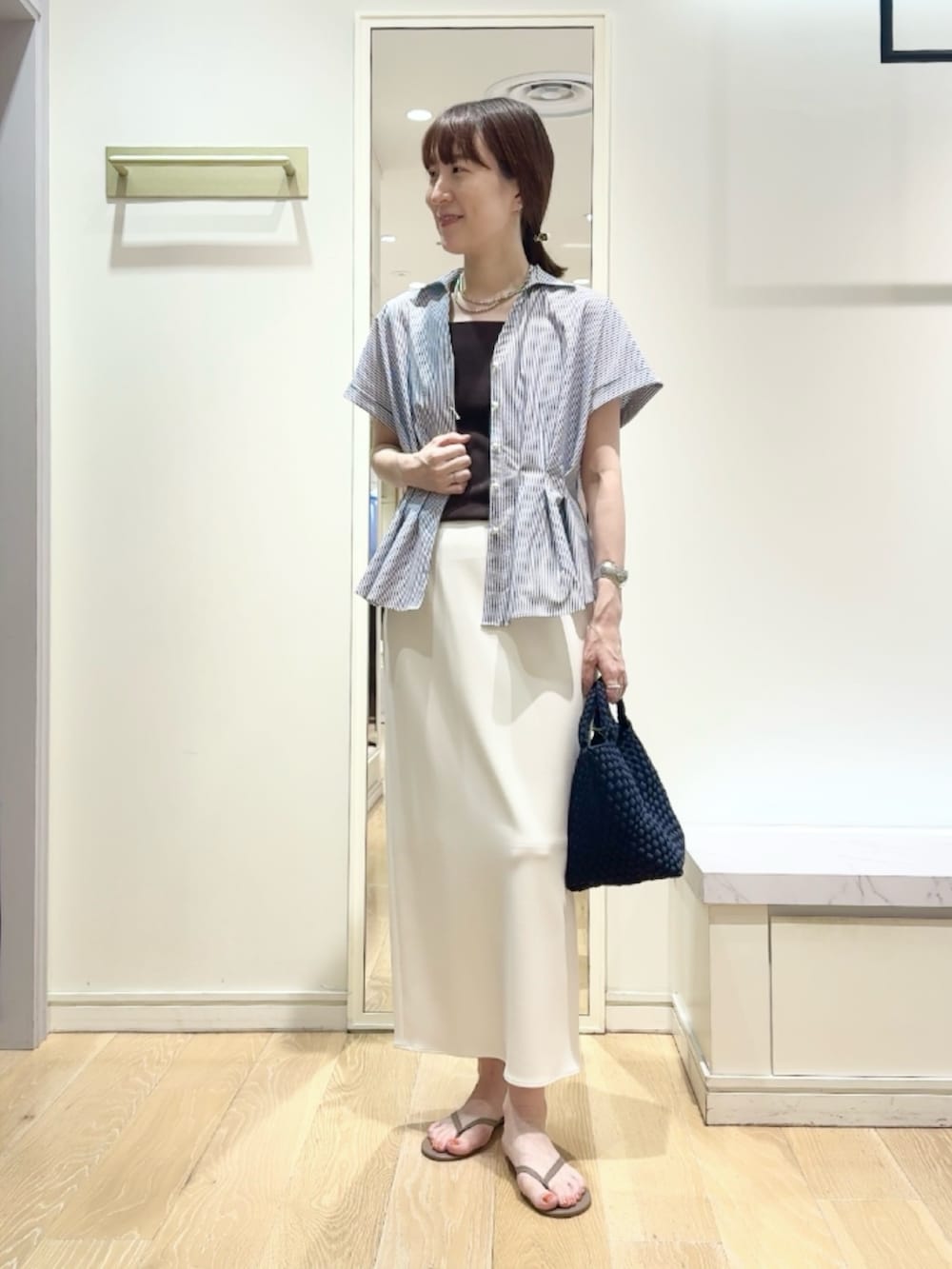ホワイト系のスカート、ブルー系のショルダーバッグ、ブルー系のシャツ/ブラウスを着用したレディースの夏コーディネートの2枚目の写真