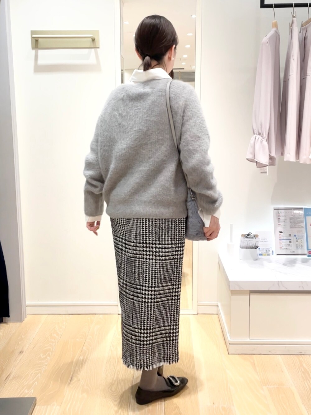 ブラック系のスカート、グレー系のニット/セーター、ブルー系のトートバッグを着用したレディースの冬コーディネートの3枚目の写真