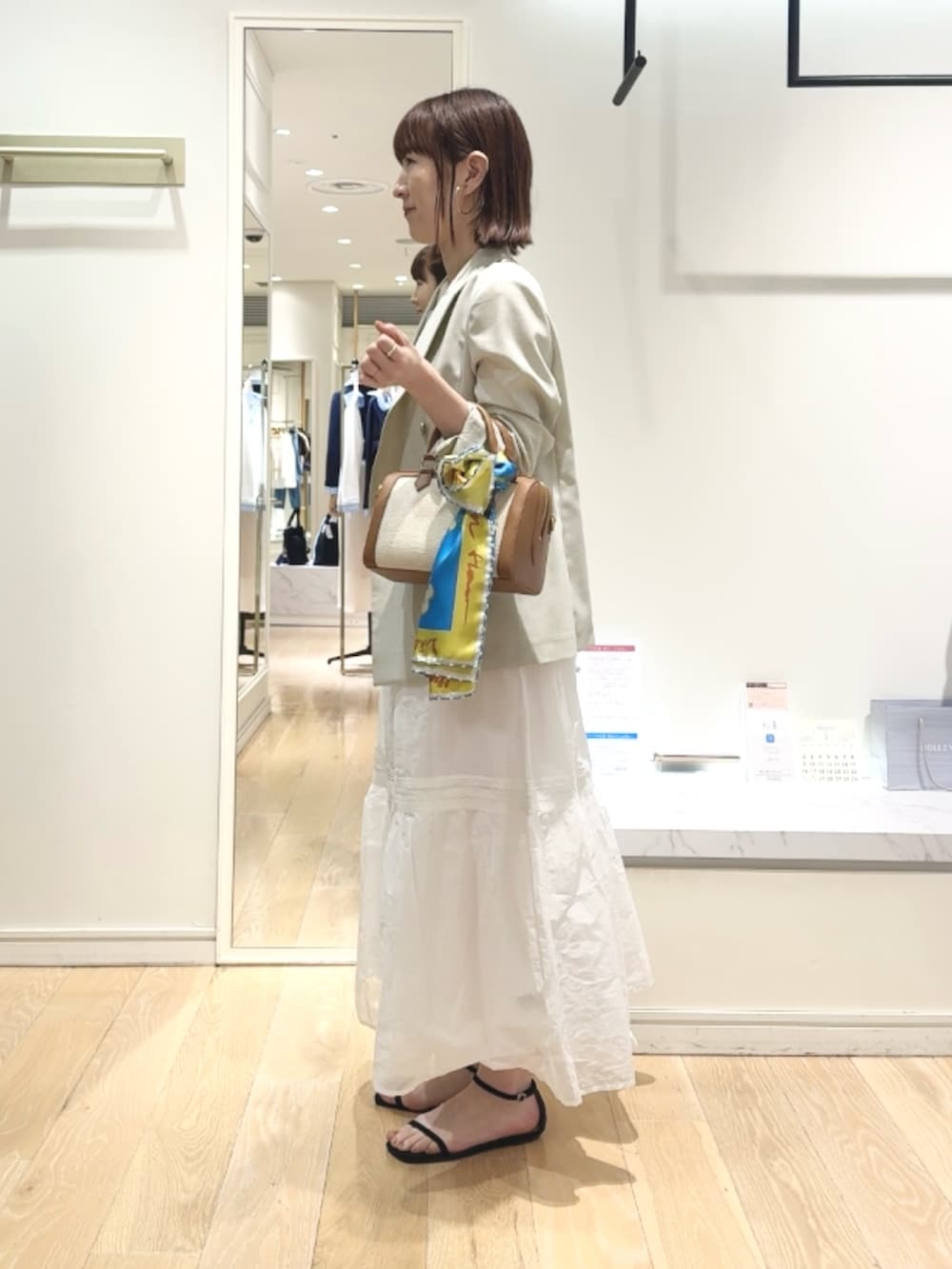 ベージュ系のテーラードジャケット、ベージュ系のタンクトップ、ブラウン系のボストンバッグを着用したレディースの春コーディネートの5枚目の写真