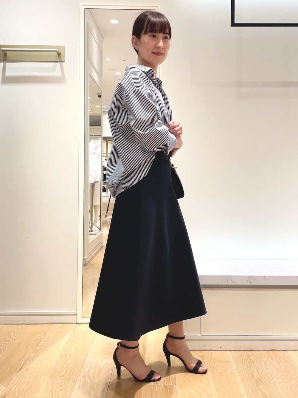 ホワイト系のシャツ/ブラウス、ブルー系のスカート、ブラック系のショルダーバッグを着用したレディースの春コーディネートの3枚目の写真